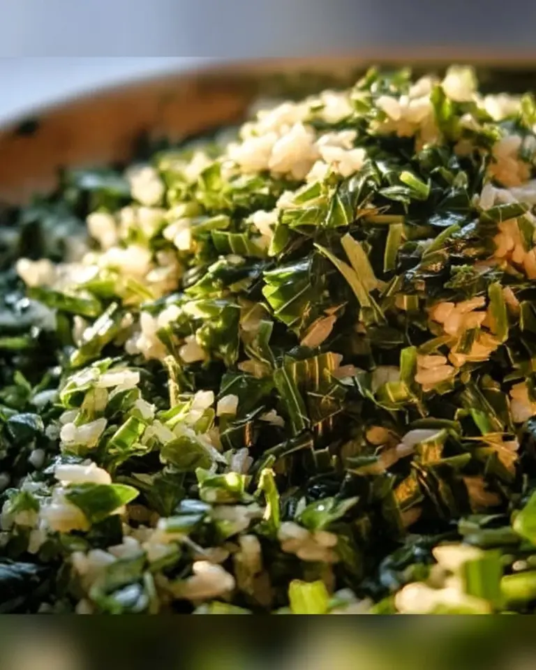 Plate of dirty rice with collards and leeks garnished with fresh herbs