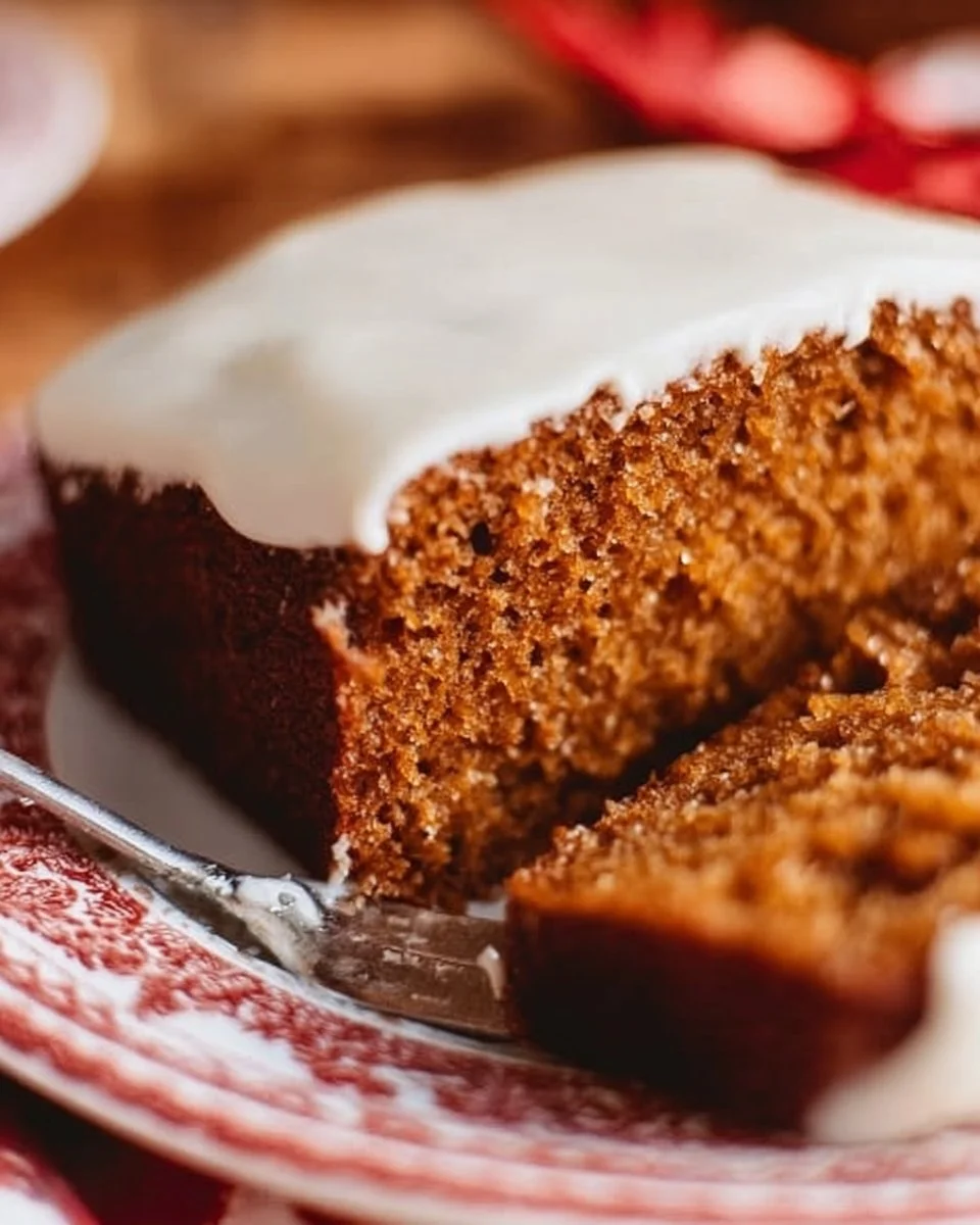 Gingerbread loaf cake topped with cream cheese frosting on a wooden table
