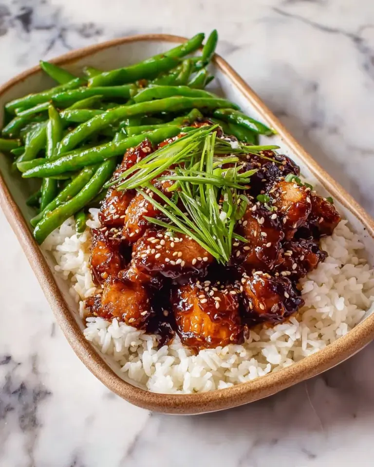 Plate of tasty high-protein sesame chicken garnished with sesame seeds and vegetables.
